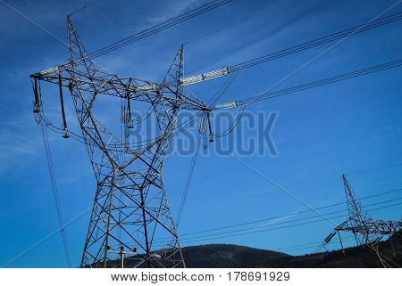 High voltage electricity cables datail over a clean blue sky