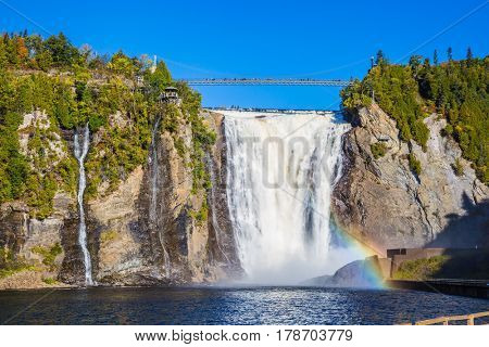 The magnificent rainbow plays in falls splashes. The concept of active and cultural tourism. The blue lake and powerful waterfall Montmorency in Montmorency Falls Park, in Quebec