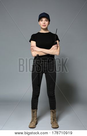 Beautiful young woman in security uniform on grey background