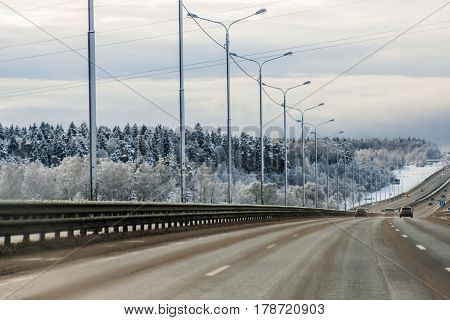 Winter road with Coniferous woodland around in blue tones