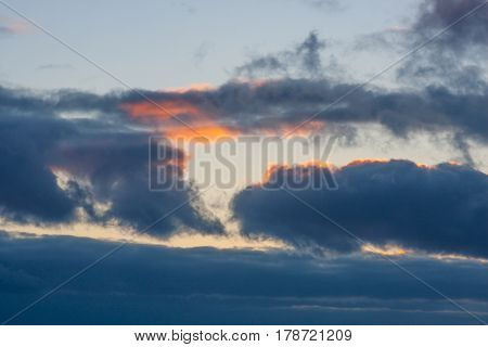 Dramatic dark blue clouds with a red sunset sunbeam in the sky