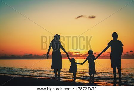 happy family with two kids walking at sunset beach