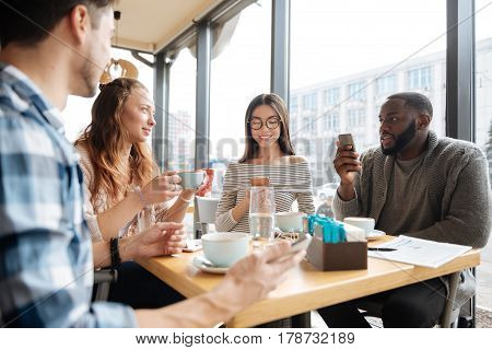 Weekend meeting. Portrait of international youngsters are spending their common time together at cafeteria by having nice conversation.