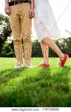 Close up photo of couple's legs in keds on grass in park. Copy space.