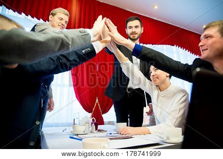 Six businessmen are highfiving each other after closing a deal
