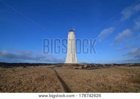 Iceland's Malarrif Lighthouse with hay fields and black lava rocks.