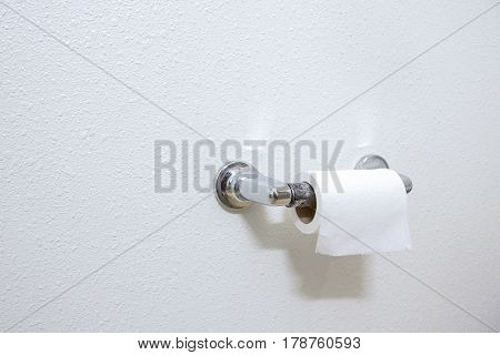 A Roll Of White Toilet Paper Hanging On A Chrome Toilet Roll Holder