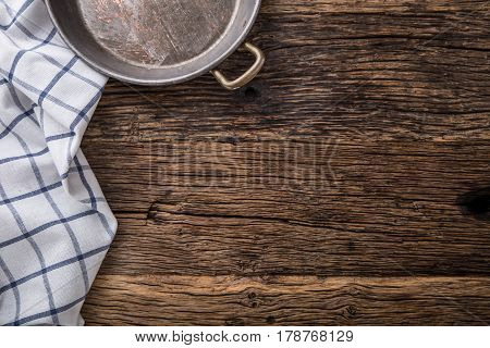 Top view of checkered tablecloth or napkin on empty wooden table.Metal old retro empty pan on oak kitchen table. Top view.