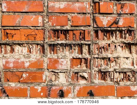 A fragment of a wall from an old red partially destroyed clay brick
