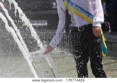 Graduate bathes in a fountain after finishing school. Inscription on the tape 