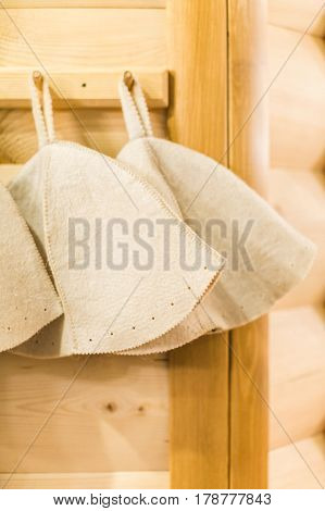 Three Russian White Wool Hats for Sauna Banya Bath House on a wooden background close up. Bath accessories in traditional Russian sauna. concept rest.