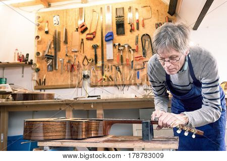 Luthier filing the frets of an acoustic guitar on the workbench