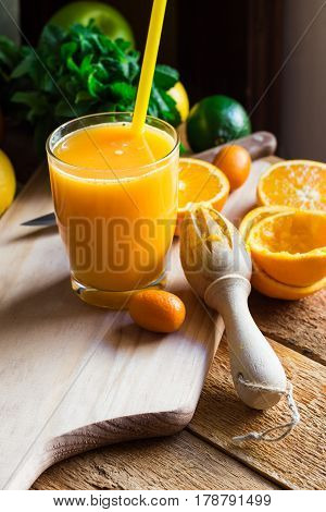 Freshly pressed citrus fruit juice from oranges lemons limes cumquat glass reamer mint on table by window daylight