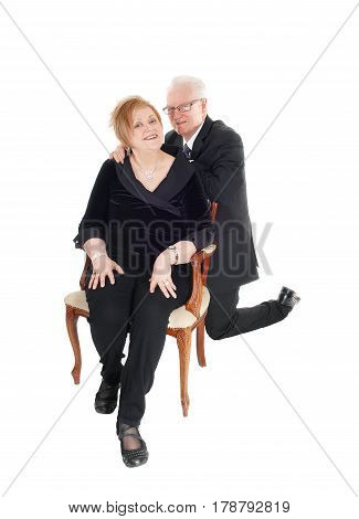 A nice senior citizen couple she sitting in an old armchair he kneeling behind her his hands on her shoulder isolated for white background.