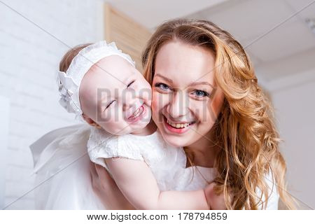 Happy mother with her daughter in white dress