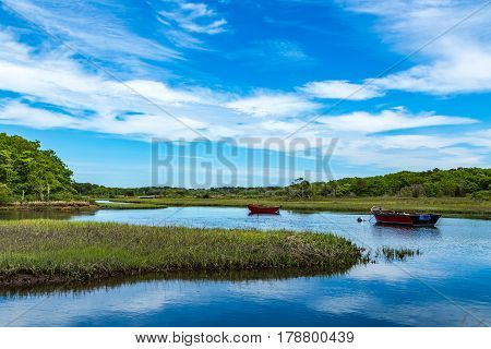 Two boats lay at anchor on the Herring River at Harwich Massachusetts on Cape Cod.