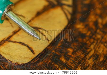Close up shot of pyrography pen over burned wood