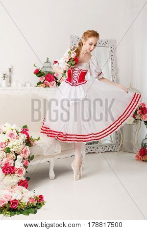 Pretty ballerina in stage costume holding a bouquet of spring flowers. Retro dress. She straightens her skirt.