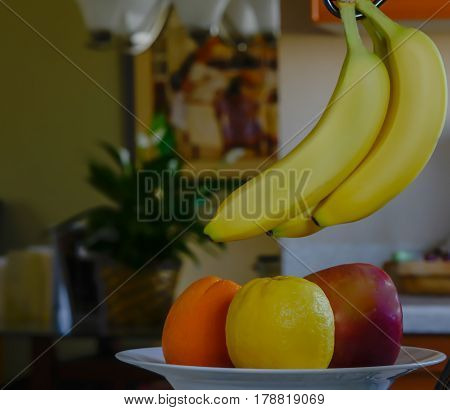 Bowl of fruit with bananas hanging over