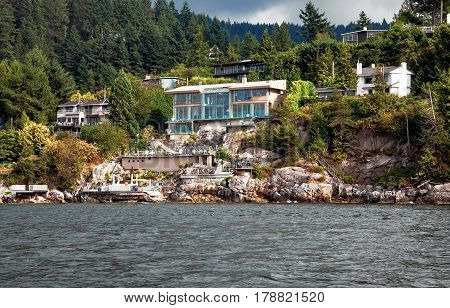 A village on a rocky beach in the  Strait of Georgia in West Vancouver  British Columbia, a coastline and a forest.