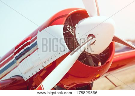 Sport airplane red and white propeller closeup outdoors on the meadow