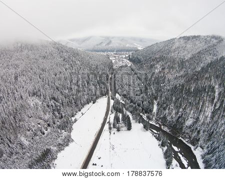 Mountain winter road that crosses the river.