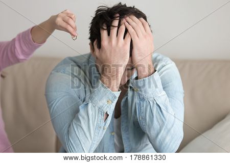 Woman gives back wedding ring to sad husband and leaving, engagement cancelling, man depressed and upset, covers face with hands. Divorce breakup concept, ending unhappy relationships, abandoned man