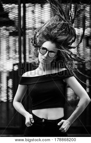 Close-up face portrait of young beautiful woman with perfect skin in Cat's eye sunglasses in the cityscape. Beauty face make-up. Hair flapping