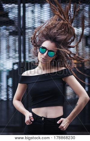 Close-up face portrait of young beautiful woman with perfect skin in Cat's eye sunglasses in the cityscape. Beauty face make-up. Hair flapping