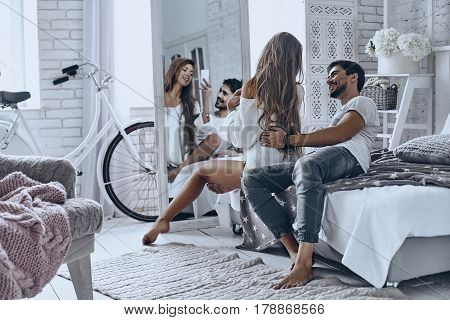 Reflection of love. Beautiful young couple resting at home and smiling while woman taking selfie in the mirror