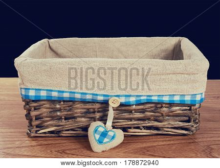 A wooden knitted basket on a wooden table on it burlap and cloth in a box, as well as a heart of burlap