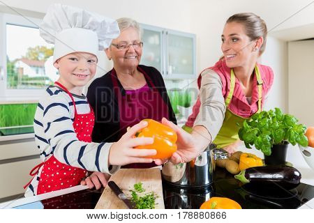 Granny, mum and son talking while cooking in kitchen