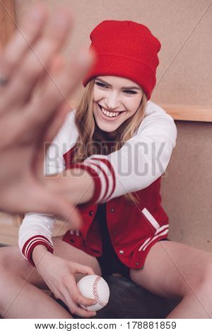 Stylish Hipster Woman In Baseball Jacket With Baseball Ball Giving Highfive