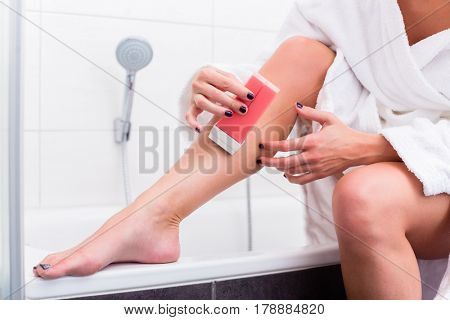 Woman in bathroom applying epilation lotion on legs