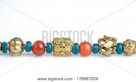 Close up ancient rare craved gold beads separated with turquoise glass beads and carnelian beads in necklace on white background