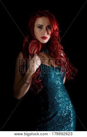 beautiful redhead woman with big tits in a tight dress posing on a dark background.