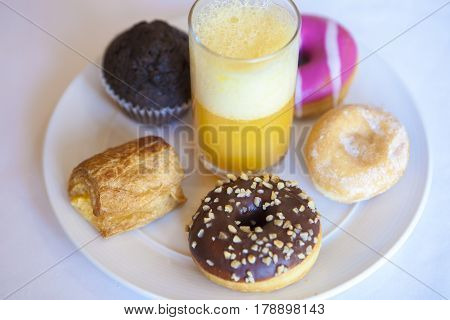 Plate full of pastries with orange juice glass. High angle view