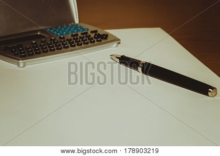 Pen calculator sheet of paper on a brown table business white