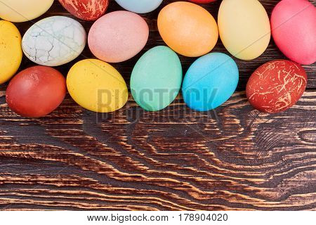 Brown wood background, Easter eggs. Colorful chicken eggs.