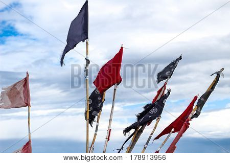 Colorful red blue and black flags on a boat or ship against blue sky with clouds at Baltic Sea in Poland