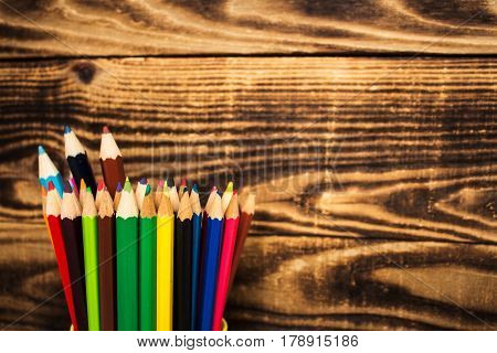 color pencil in a cup on wooden background