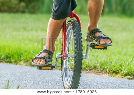 outdoor portrait of young boy riding a unicycle (one wheel bike) on natural background
