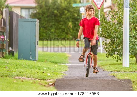 outdoor portrait of young boy riding a unicycle (one wheel bike) on natural background