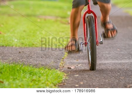 outdoor portrait of young boy riding a unicycle (one wheel bike) on natural background