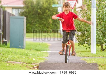 outdoor portrait of young boy riding a unicycle (one wheel bike) on natural background