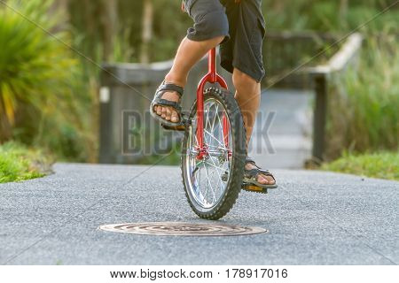 outdoor portrait of young boy riding a unicycle (one wheel bike) on natural background