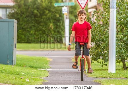 outdoor portrait of young boy riding a unicycle (one wheel bike) on natural background