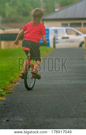 outdoor portrait of young boy riding a unicycle (one wheel bike) on natural background