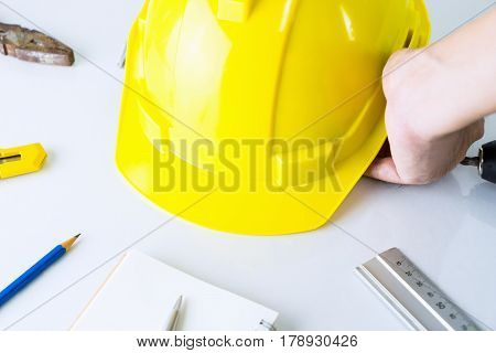 Construction worker is picking up safety helment from tool desk
