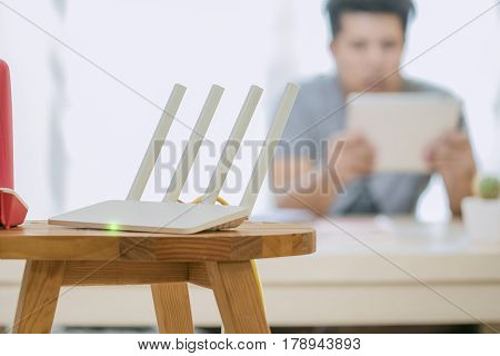 closeup of a wireless router and a man using Tablet on living room at home ofiice